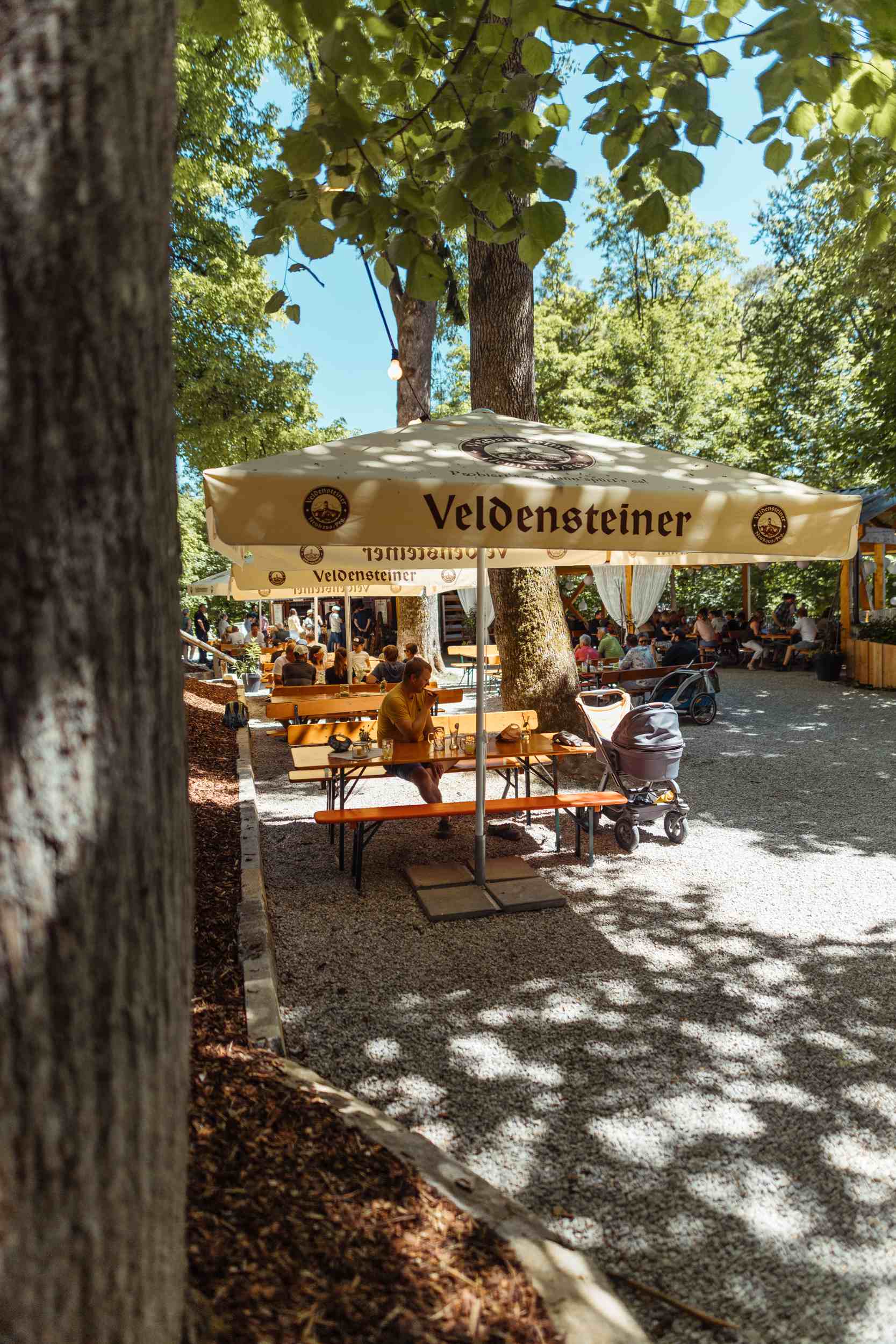 Bierschirm im Sonnenlicht über Holztischen im Biergarten
