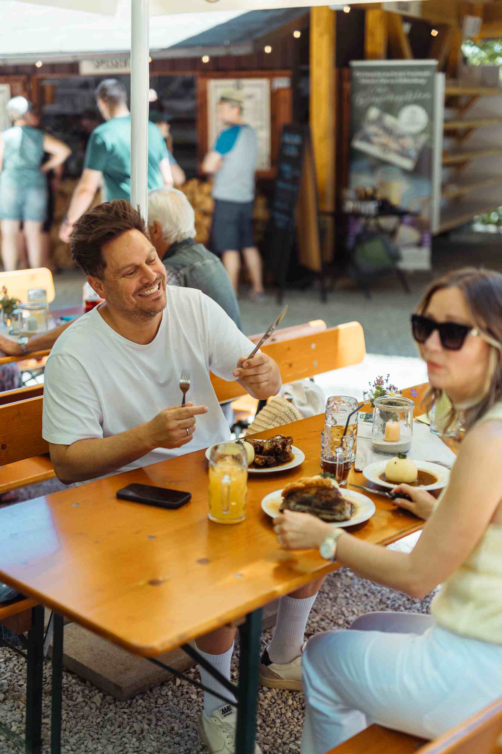 Lachendes Paar beim Essen im Biergarten